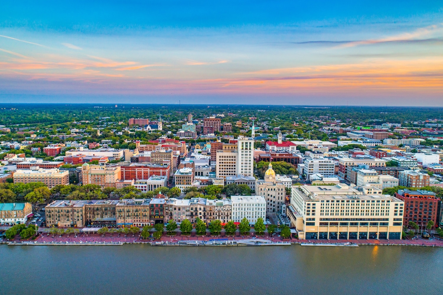 Downtown Savannah Georgia skyline with the river in front and a blue partly cloudy sky in the background