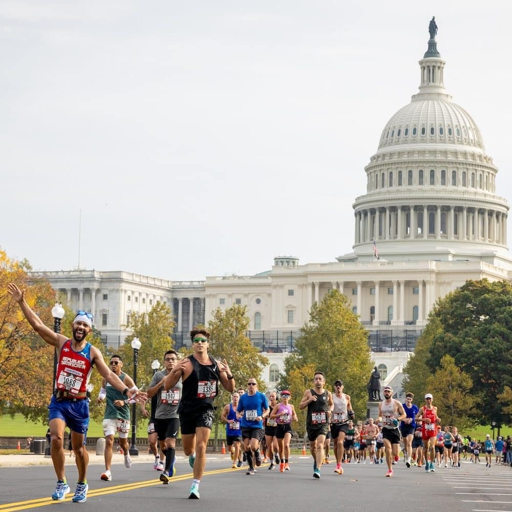 Runners running in a race on a road with the United States Capitol in the background